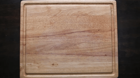 Demonstrates placing a damp paper towel under the cutting board.
