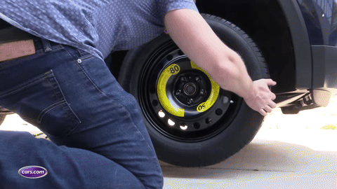 Installing the spare tire and hand tightening the lug nuts.
