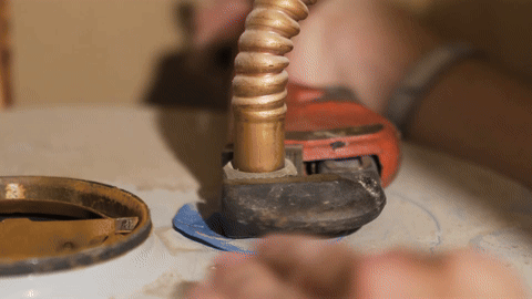 Using tools to disconnect the water lines from the top of the heater.