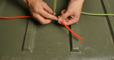 Demonstrates the first step of tying the square knot by crossing the rope ends.