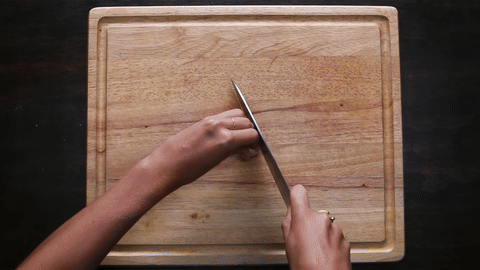 Demonstrates smashing and peeling garlic.