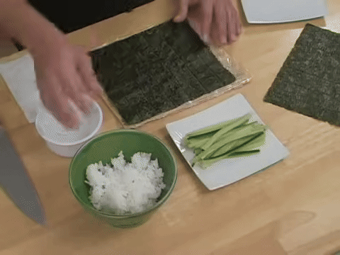 Shows the process of adding sticky rice to the seaweed and using water to manage stickiness.
