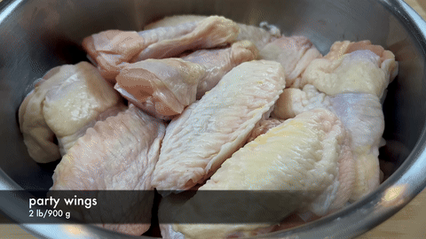 Shows rinsing and patting dry of chicken wings.