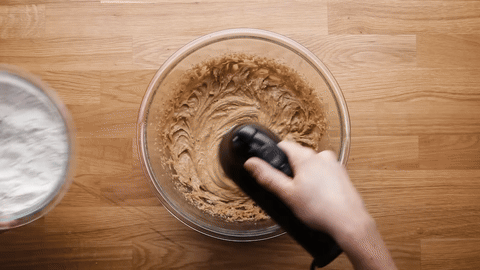 Adding dry ingredients to the wet mixture in parts.