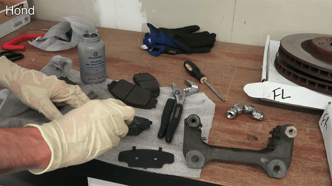 Demonstrates the application of lubricant to brake pads.