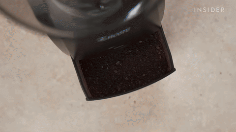 Shows measuring coffee grounds with a tablespoon.