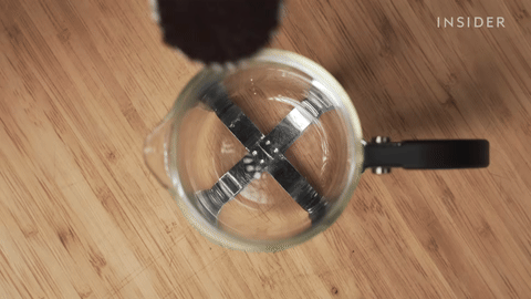 Shows adding coffee grounds to the French press.