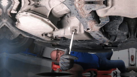 Process of removing the drain plug and oil draining into the pan.