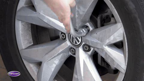 Removing the flat tire after loosening lug nuts.