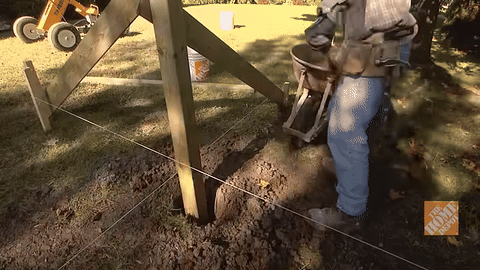 Shows mixing and pouring concrete into the post hole.
