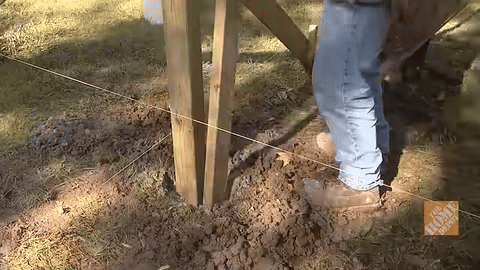 Demonstrates tamping the concrete with a two by four.