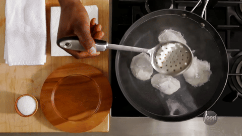 Shows the final step of scooping out and serving the poached eggs.