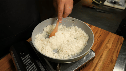 Frying rice in oil until it releases a nutty aroma.