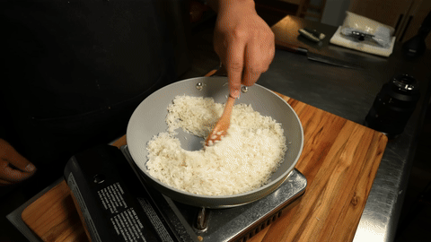Adding water and strained salsa to the rice.