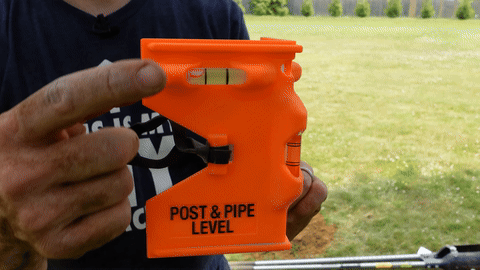 Illustrates leveling the post using a post and pipe level and securing it with wood pieces.