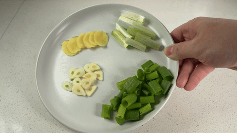 Shows the slicing of aromatics and preparation of the stir fry sauce.